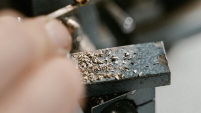 Zbliżenie na kobietę pracującą przy obróbce metalu w warsztacie przemysłowym.