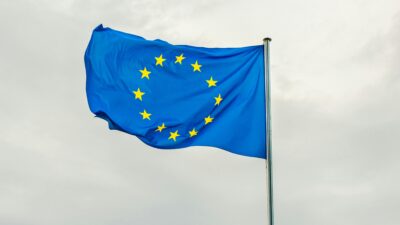 Flaga Unii Europejskiej powiewająca na tle pochmurnego nieba.