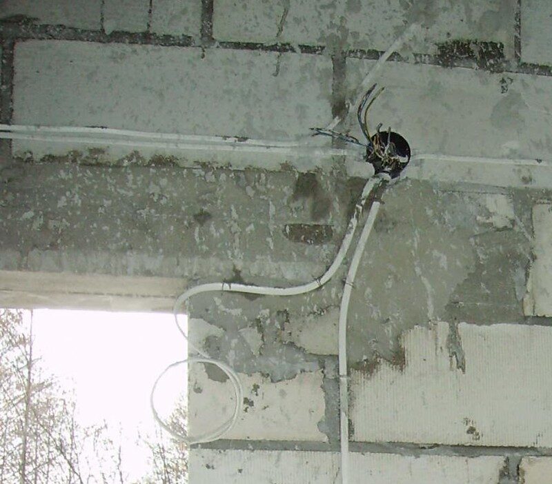 Instalacja elektryczna w ścianie z widoczną puszką i przewodami, symbolizująca wymagane uprawnienia SEP do pracy z elektryką.